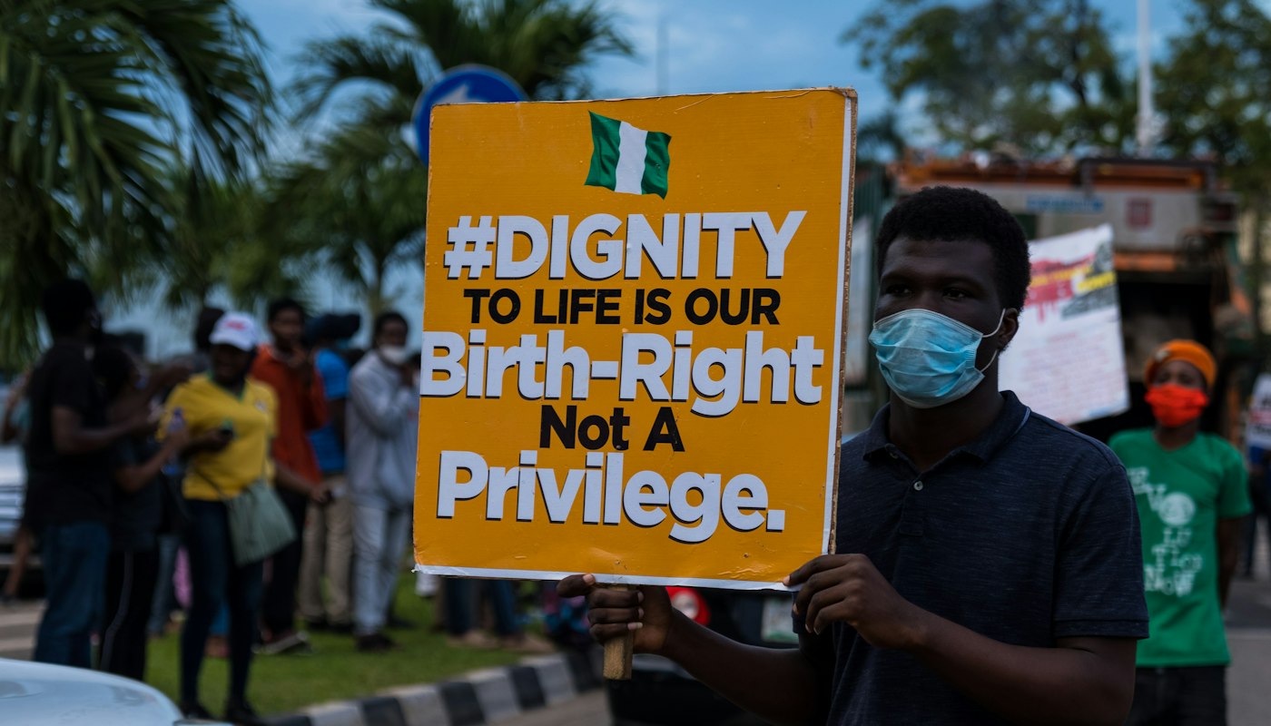 A man holding a sign that reads dignity to life is our birth-right, not a privilege